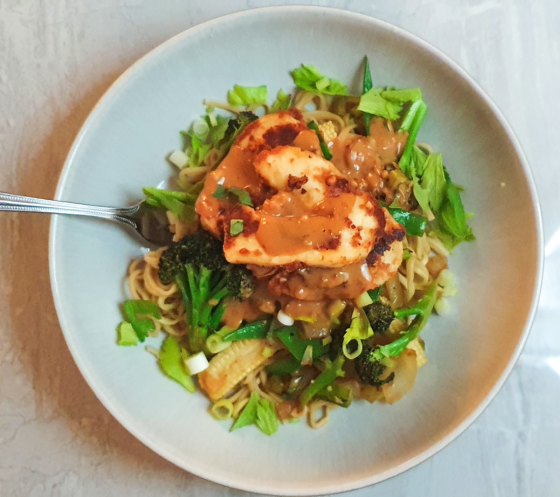 stir fried vegetables with crispy halloumi and satay sauce in a white bowl on a whit background