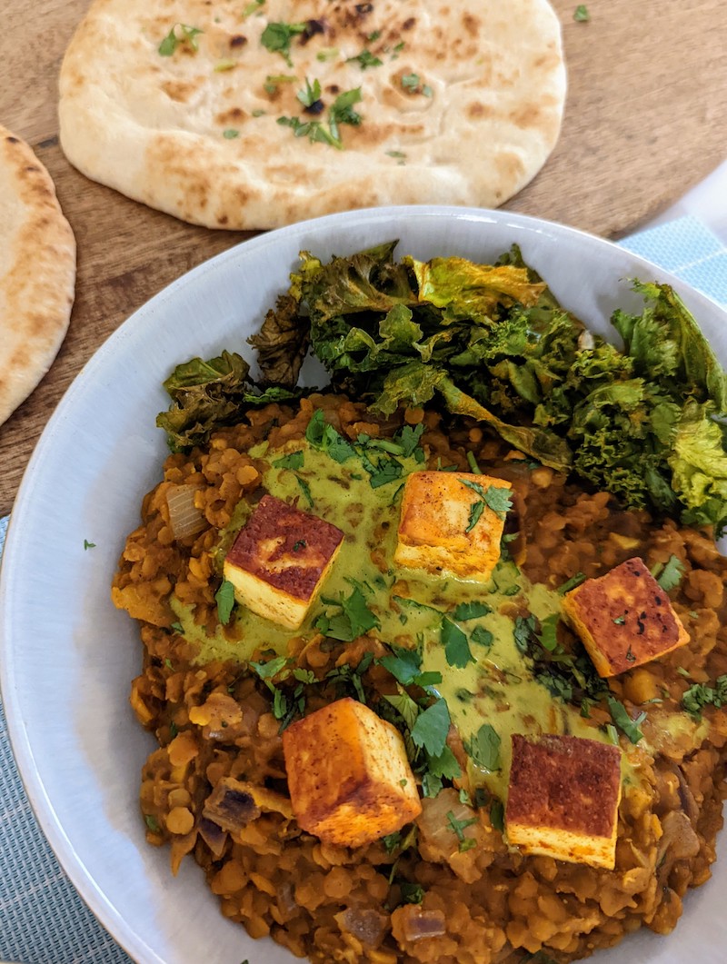 fried paneer on red lentil dahl with crispy kale all served in a bowl 